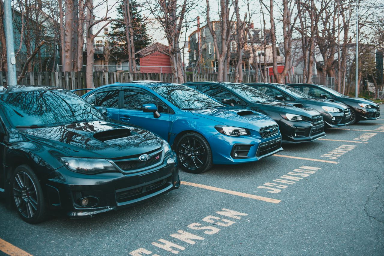about-02 Multiple Subaru cars parked in an outdoor lot lined with trees, showcasing automotive design.